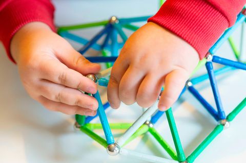 Kind spielt mit Magnetspielzeug bestehend aus Stäben und magnetischen Kugeln