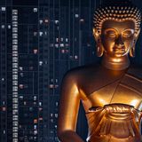 übergroße glänzendgoldene Buddhastatue, in der Nacht angeleuchtet. Dahinter Hochhaus mit beleuchteten Fenstern