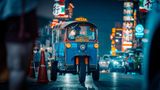 Dreirädriges Tuk-Tuktuk mit Fahrer in einer Straße, Neonreklamen, Nachtstimmung