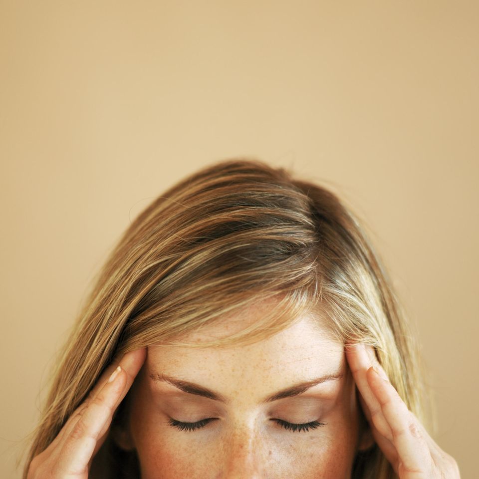 Frau fasst sich mit beiden Händen an den Kopf  Frau fasst sich mit beiden Händen an den Kopf