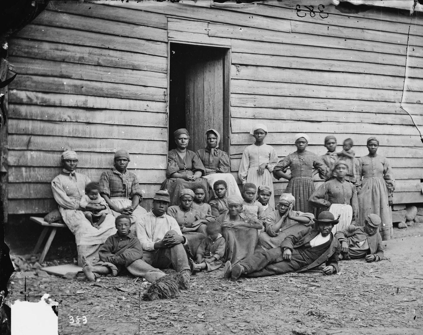 Harriet Beecher Stowe: "Onkel Toms Hütte" Eine Gruppe von Personen steht und sitzt vor einem Holzhaus