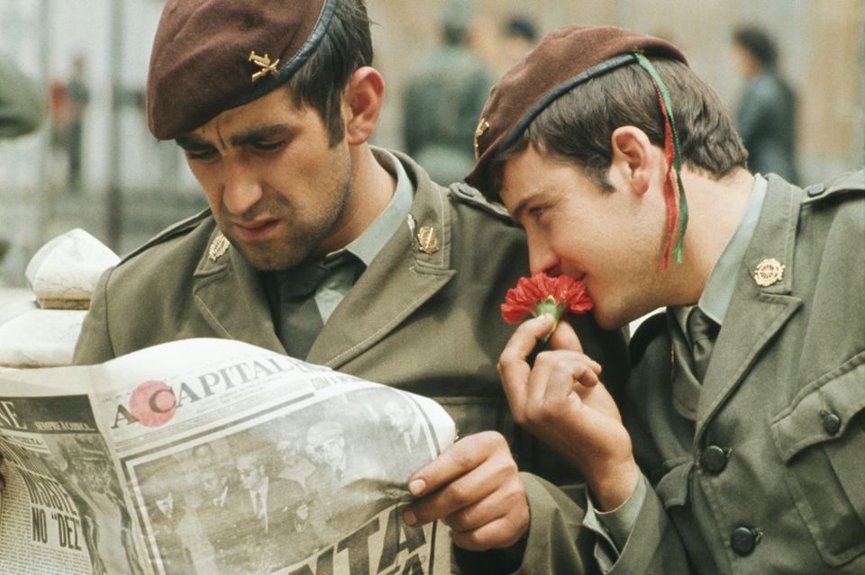 Wie süß riecht die Freiheit: Einen Tag nach dem Beginn der "Nelkenrevolution" informieren sich zwei aufständische Soldaten über die Pläne der neuen Regierung