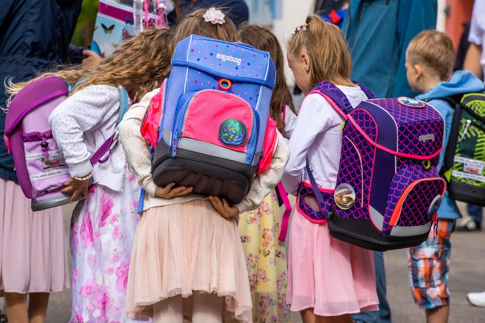 Mädchen von hinten mit Schulranzen auf dem Rücken 1.5159