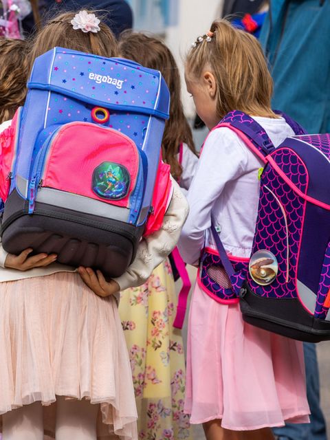 Mädchen von hinten mit Schulranzen auf dem Rücken