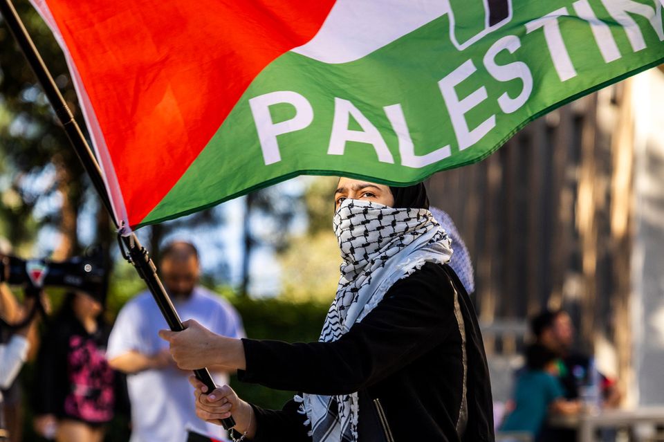 Caption/Abstract=IRVINE, CA - APRIL 29, 2024: A  protester carries a Palestinian flag in solidarity with a pro-palestinian encampment nearby  in the central part of the UC Irvine campus on April  29, 2024 in Irvine, California.