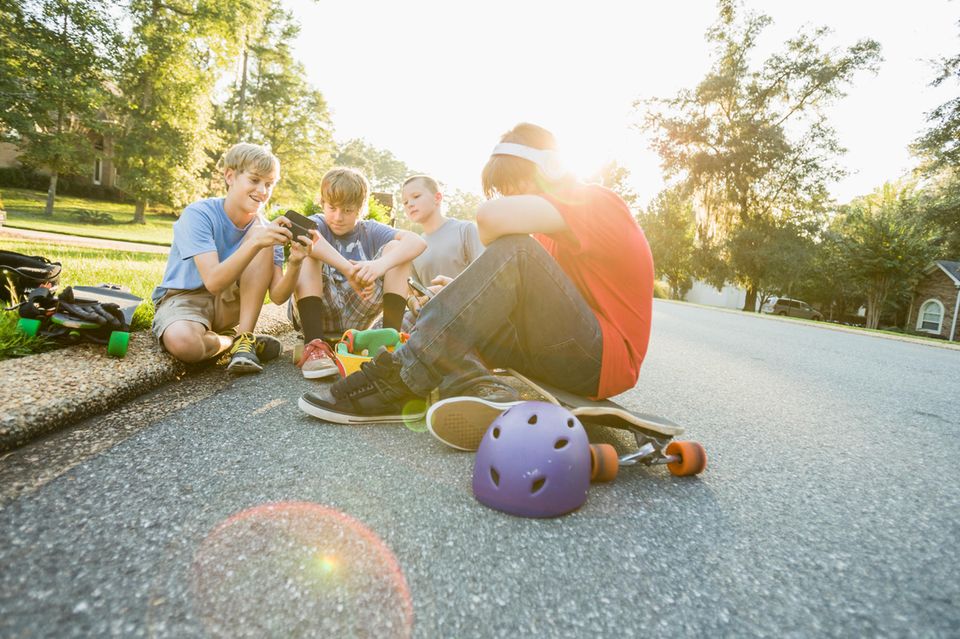 Eine Gruppe von Kindern sitzt beisammen und zeigt sich Inahlte auf dem Smartphone  1.5004