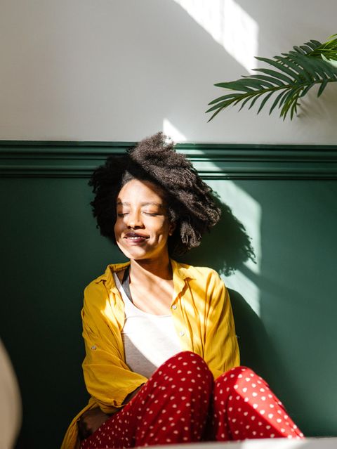 Eine Frau sitzt zu Hause auf dem Boden und lächelt