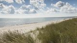 Düne direkt am Wasser bei wolkenbedecktem Himmel