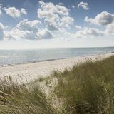 Düne direkt am Wasser bei wolkenbedecktem Himmel