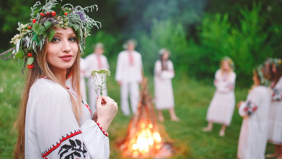 Eine Gruppe steht im Kreis um ein Feuer herum und feiert Mittsommer . Eine Gruppe steht im Kreis um ein Feuer herum und feiert Mittsommer .