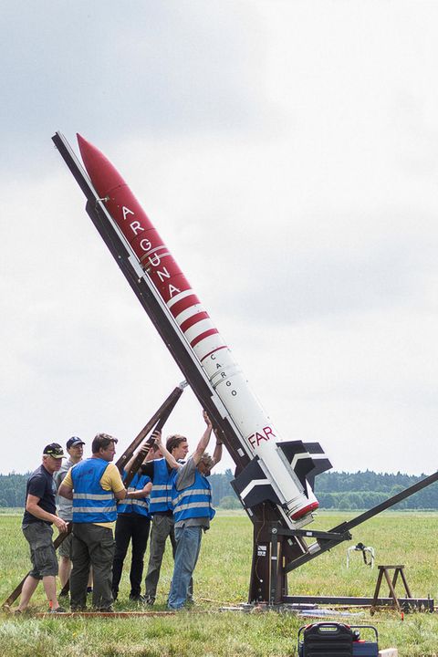 Eine Gruppe Männer stellt eine Rakete aufrecht
