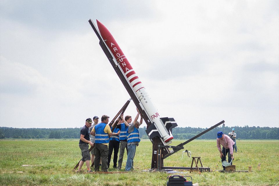 Eine Gruppe Männer stellt eine Rakete aufrecht