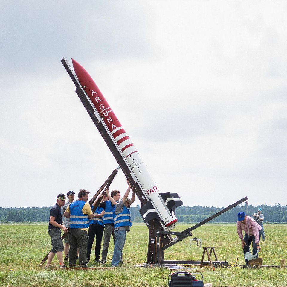 Eine Gruppe Männer stellt eine Rakete aufrecht  Eine Gruppe Männer stellt eine Rakete aufrecht