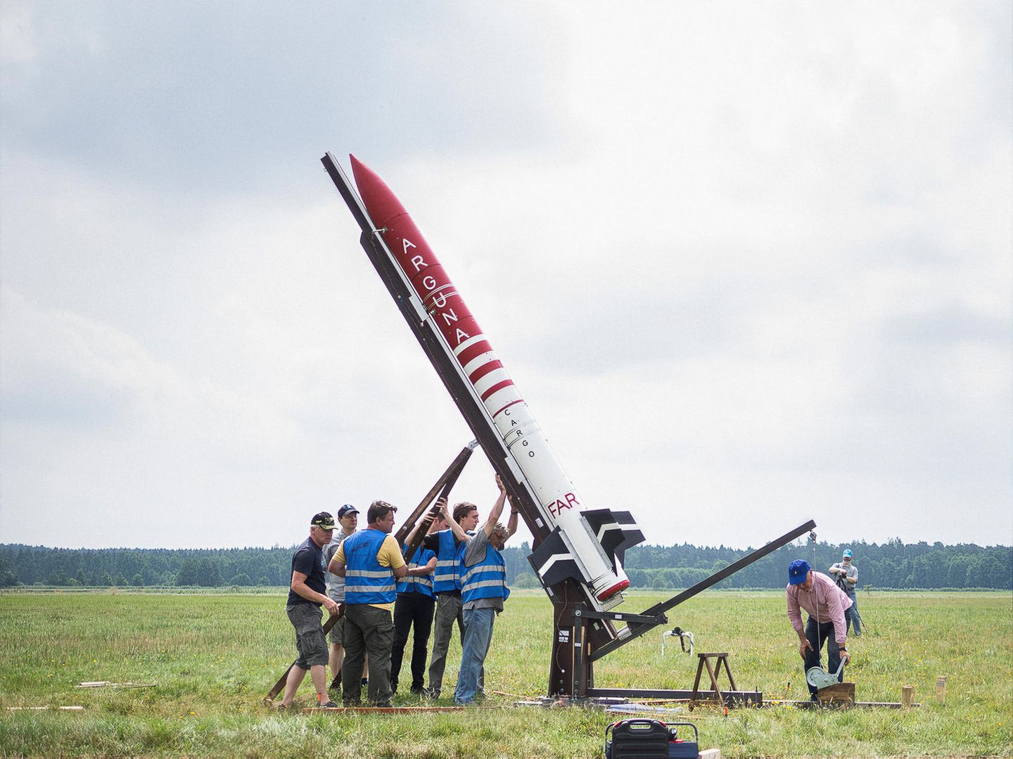 Eine Gruppe Männer stellt eine Rakete aufrecht