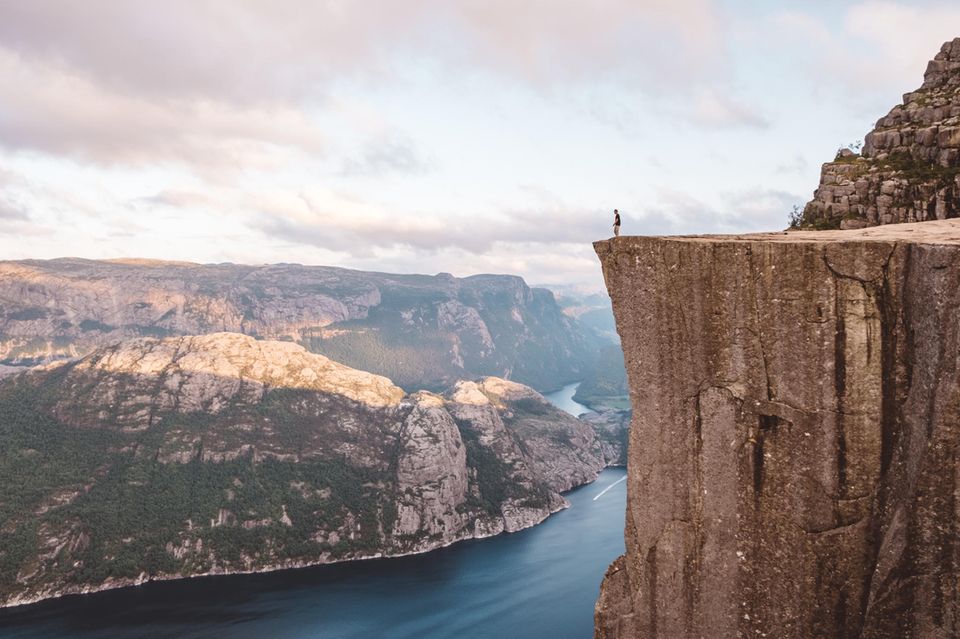 Mensch auf flachem Felsen, Abgrund, unten (600 Meter tiefer) der Fjord