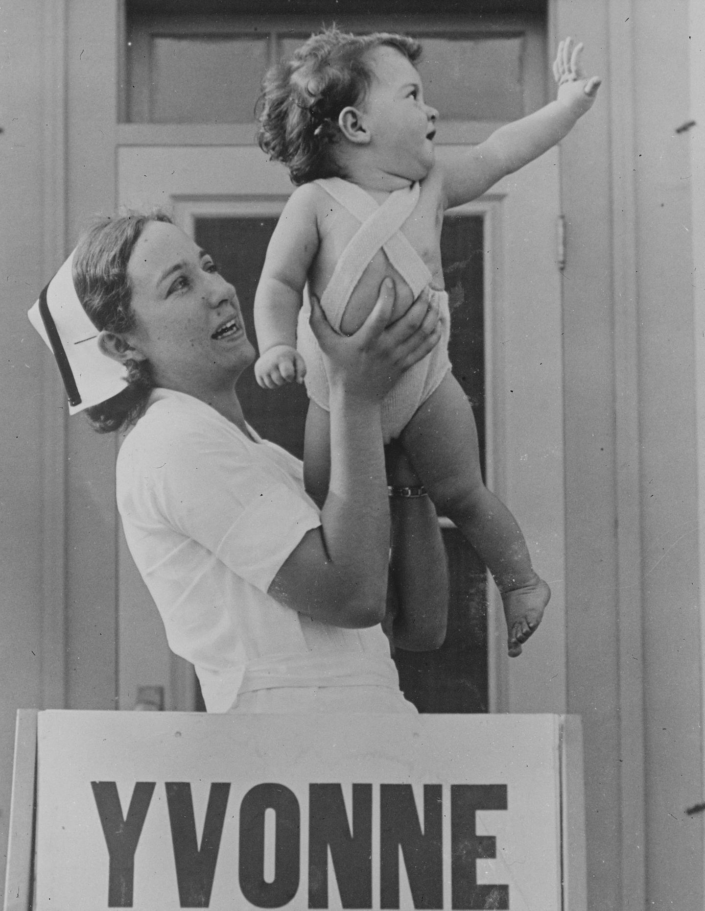 Yvonne winkt glücklich mit einem Dionne Baby auf dem Arm 1935