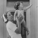 Yvonne winkt glücklich mit einem Dionne Baby auf dem Arm 1935