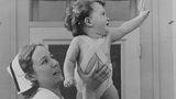 Yvonne winkt glücklich mit einem Dionne Baby auf dem Arm 1935