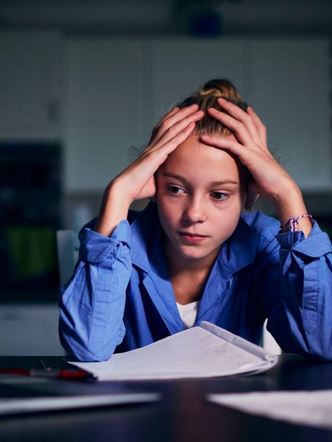 Junge Frau sitzt, mit Kopf in den Händen gestützt, vor dem Laptop