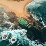 Sandbank, die in Felsen ausläuft, Pools von oben, dahinter das Meer