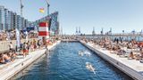 Großes Becken im Hafen, dahinter sieht man Hochhäuser und Kräne