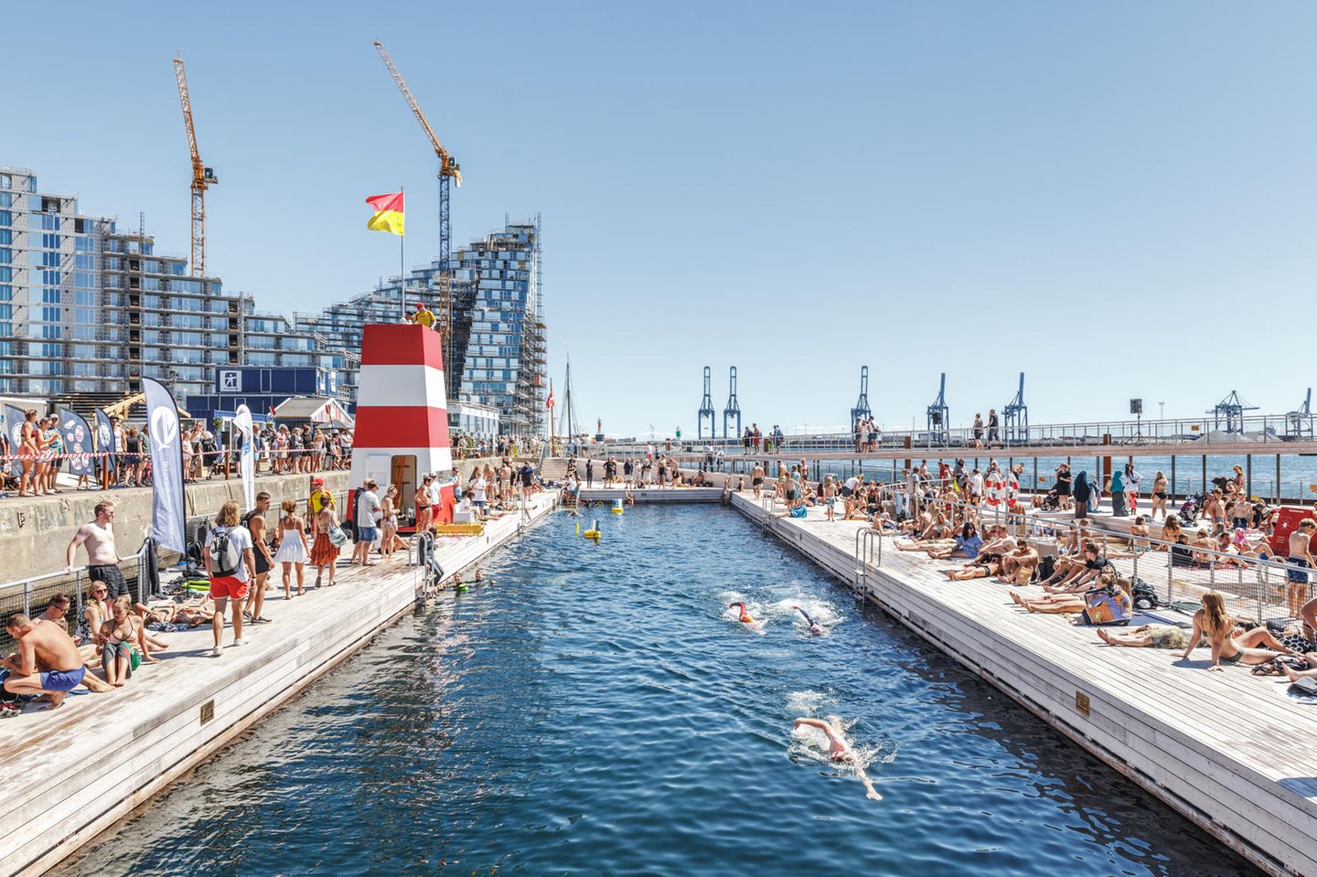Großes Becken im Hafen, dahinter sieht man Hochhäuser und Kräne