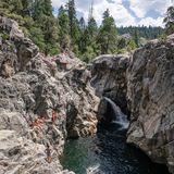 Menschen schwimmen im Fluss zwischen hohen Felsen, kleiner Wasserfall