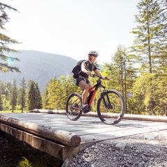 Eine Frau fährt mit ihrem Mountain Bike über eine Brücke