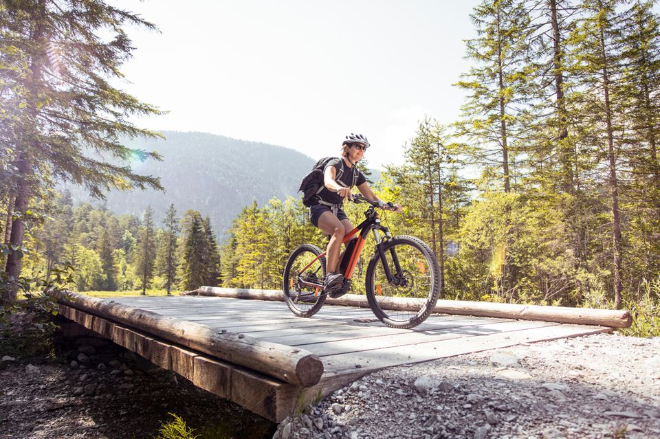 Eine Frau fährt mit ihrem Mountain Bike über eine Brücke