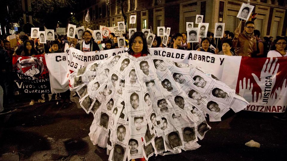 Eine Mexikanerin hat sich Plakate vermisster Studenten umgehängt