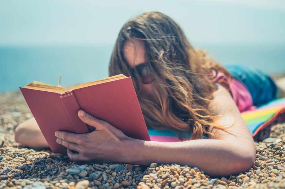 Junge Frau liest Buch am Strand  1.3333