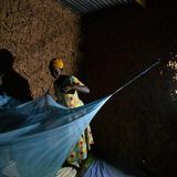 Im Schein ihrer Solarlampe breitet eine Mutter Moskitonetze über den Betten ihrer Kinder aus. Die Lampe hat sie im Solarkiosk aufgeladen – die einzige Energiequelle im Dorf