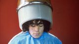 Diego Maradona sitzt beim Friseur, auf dem Kopf eine Trockenhaube