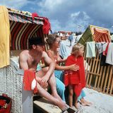 Uwe Seeler sitzt in einem Strandkorb, neben ihm seine Frau, die die Tochter abtrocknet