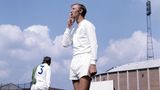 Jack Charlton steht in Sportkleidung auf einem Trainingsplatz und raucht