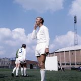 Jack Charlton steht in Sportkleidung auf einem Trainingsplatz und raucht