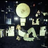 Günter Netzer liegt lässig vor einer schwarzen Schrankwand mit Büchern und Objekten