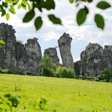 Sandsteinfelsen mit Brücke und Mensch, davor eine Wiese