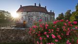 Historische Steinburg mit Fensterläden, Rosenbüsche im Vordergrund
