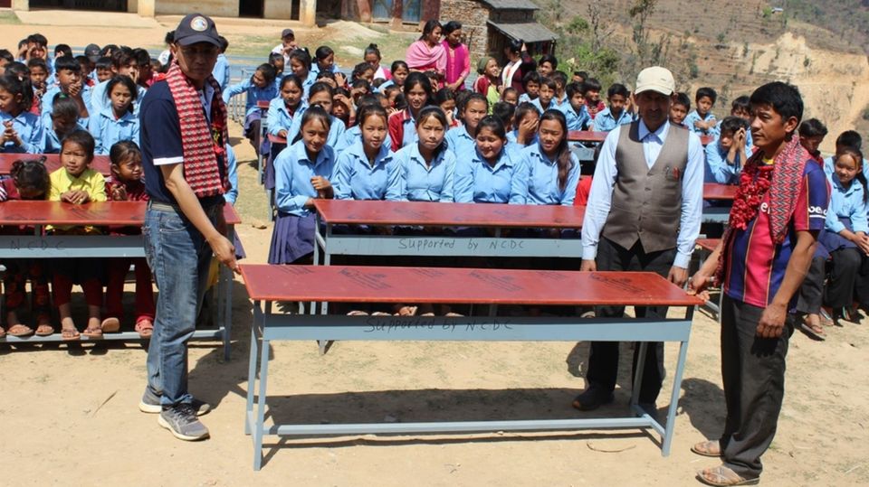 Neue Schulbänke für Grundschule Der örtliche Projektleiter Dr. Bajracharya übergibt der Grundschule in Danda Basaha die neuen Schulbänke