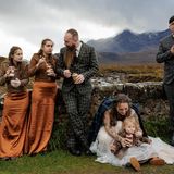 Eine Gruppe von Männern und Frauen stehen an einer Mauer und essen  Kuchen