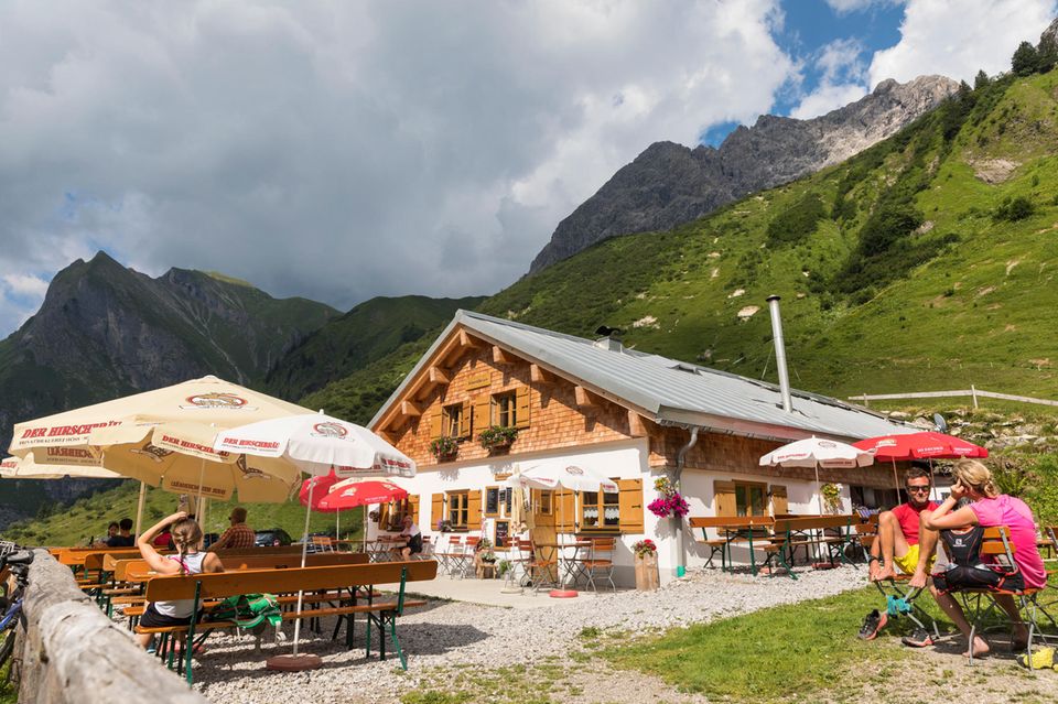 Almhütte mit Bänken und Sonnenschirmen