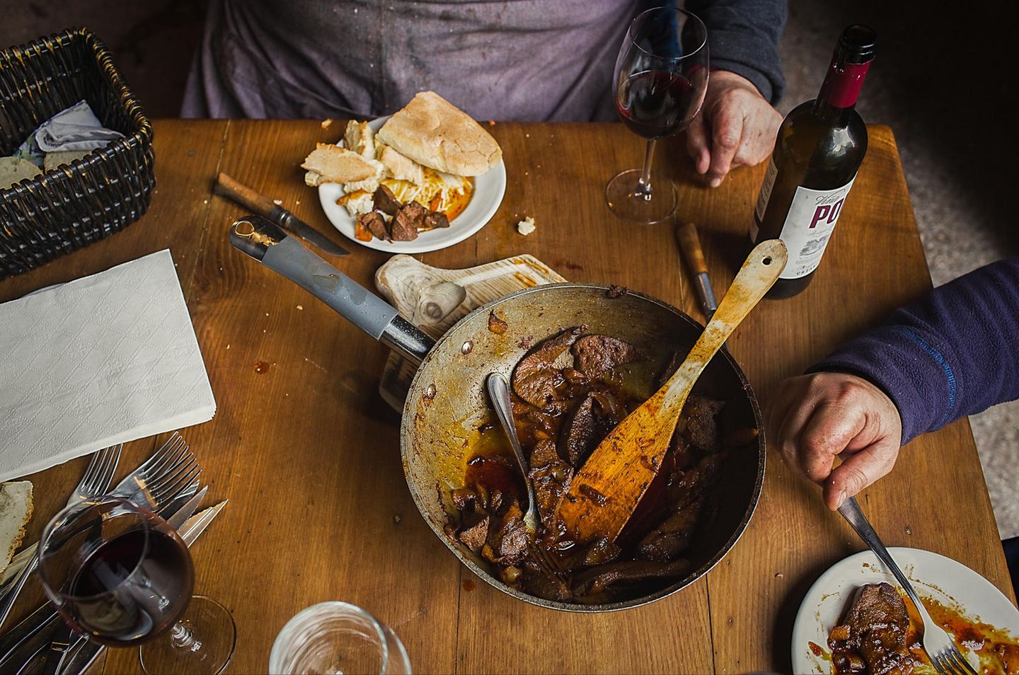 Ein letztes Abendmahl Pfanne mit Fleisch und Teller mit Brot und Glas mit Rotweinflasche auf einem Tisch