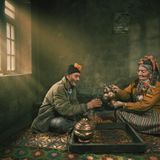 Altes asiatisches Paar sitz beim Teetrinken auf dem Boden in einem Raum