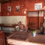 Junger Mann sitzt in einem leeren Laden mit Früchten auf dem Tisch