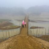 Zwei Menschen gehen über eine  Brücke und halten pinkfarbene Süssigkeiten hoch