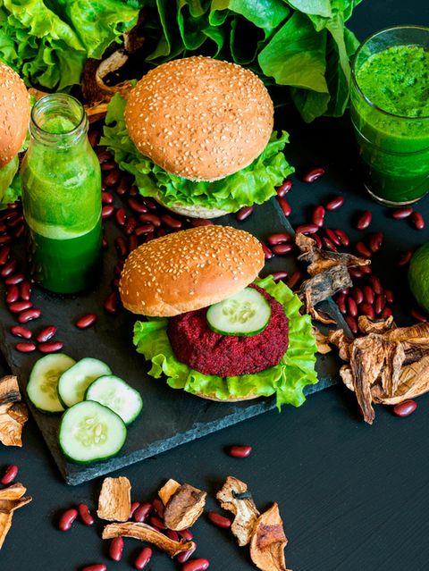 Vegane Hamburger mit Gemüse und grünem Smoothie auf schwarzem Untergrund