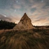 Sternenhimmel, vorne ein Felsen mit geschichtetem Sedimentgestein