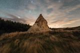 Sternenhimmel, vorne ein Felsen mit geschichtetem Sedimentgestein