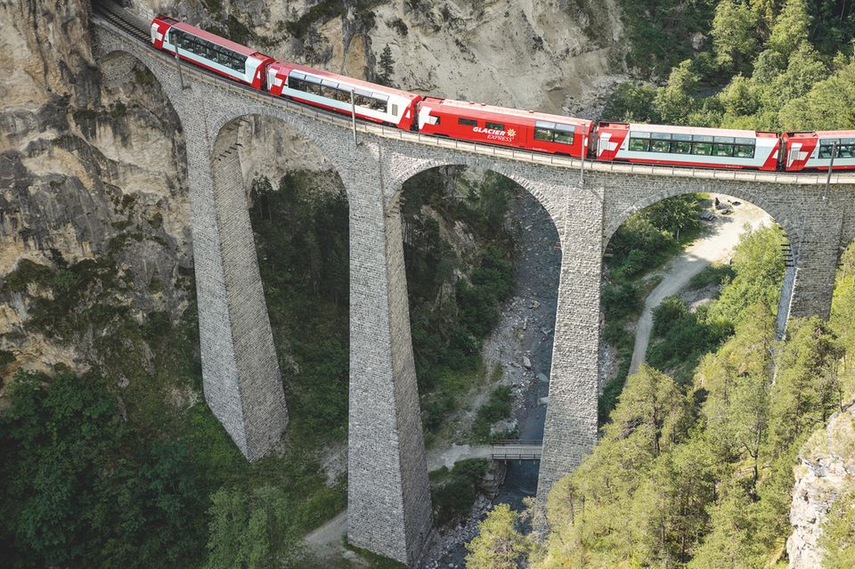 Viadukt, Felsen, Schlucht. Über die Brücke fährt ein Zug.